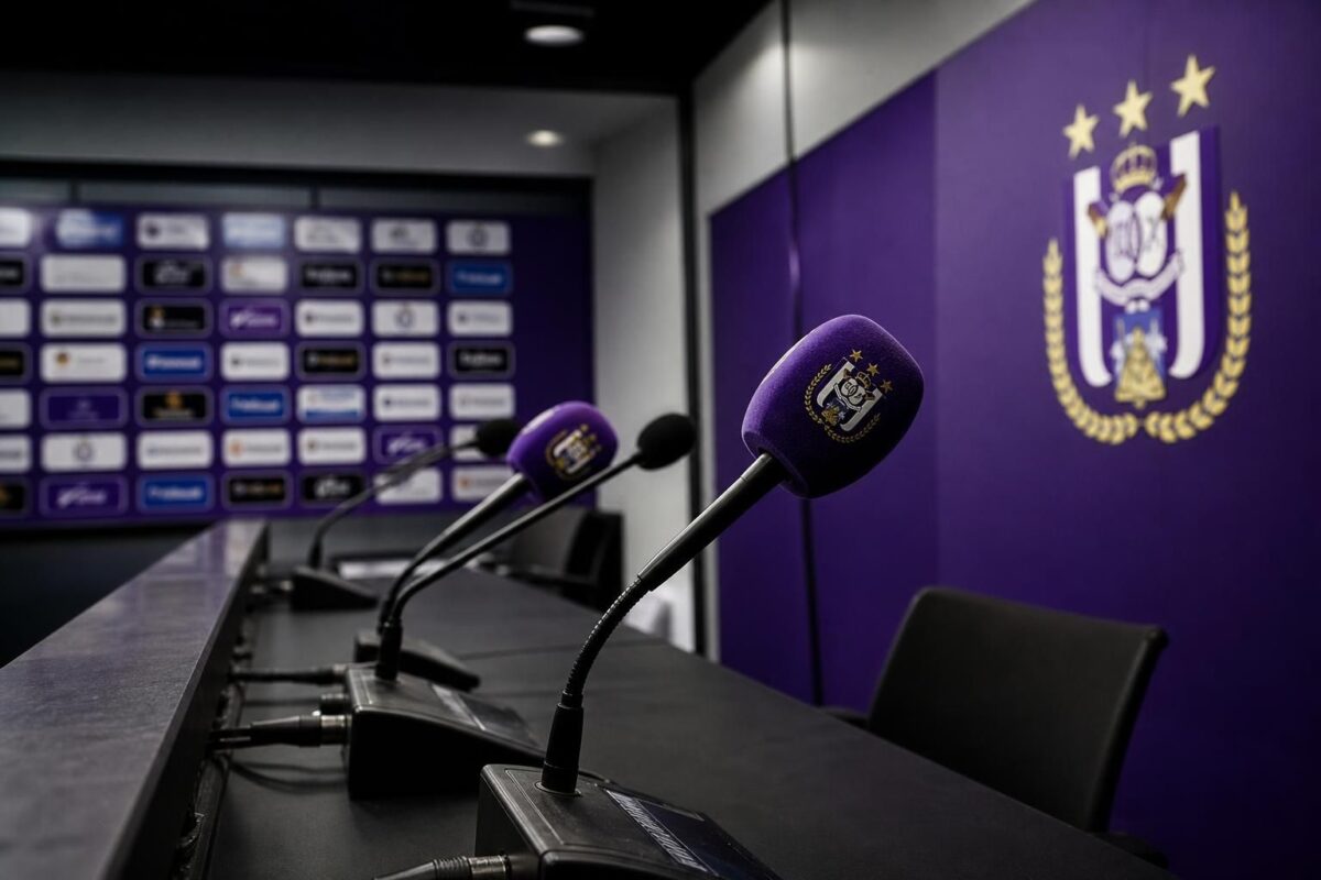 Persmoment in een Anderlecht-context met microfoons en paars-witte voetbalsetting