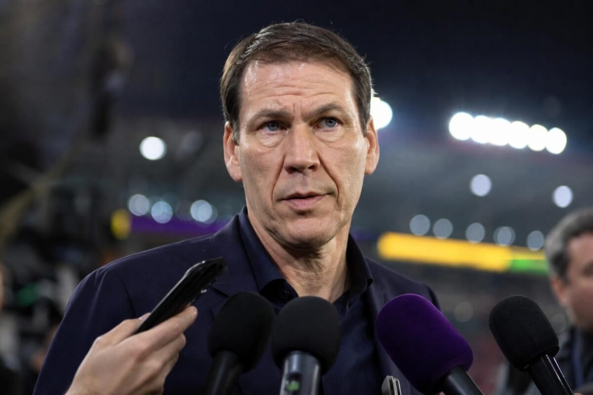 Rudi Garcia in een gespannen voetbalcontext met persmicrofoons en stadionlicht.