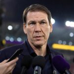 Rudi Garcia in een gespannen voetbalcontext met persmicrofoons en stadionlicht.