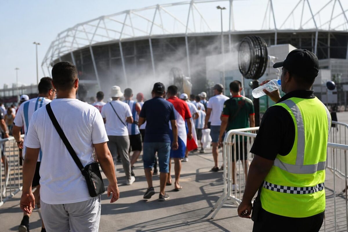 Supporters aan een zonnig WK-stadion met focus op hitte en veiligheidsmaatregelen