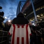 Transfercontext rond PSV en Bayern München met perscamera's en clubkleuren zonder herkenbare gezichten