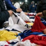 Supporters bekijken voetbalshirts in een drukke voetbalomgeving zonder herkenbare gezichten