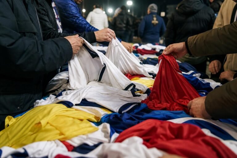 Supporters bekijken voetbalshirts in een drukke voetbalomgeving zonder herkenbare gezichten