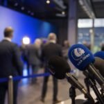 Persmoment in een voetbalstadion rond KAA Gent en de discussie over de competitiehervorming.