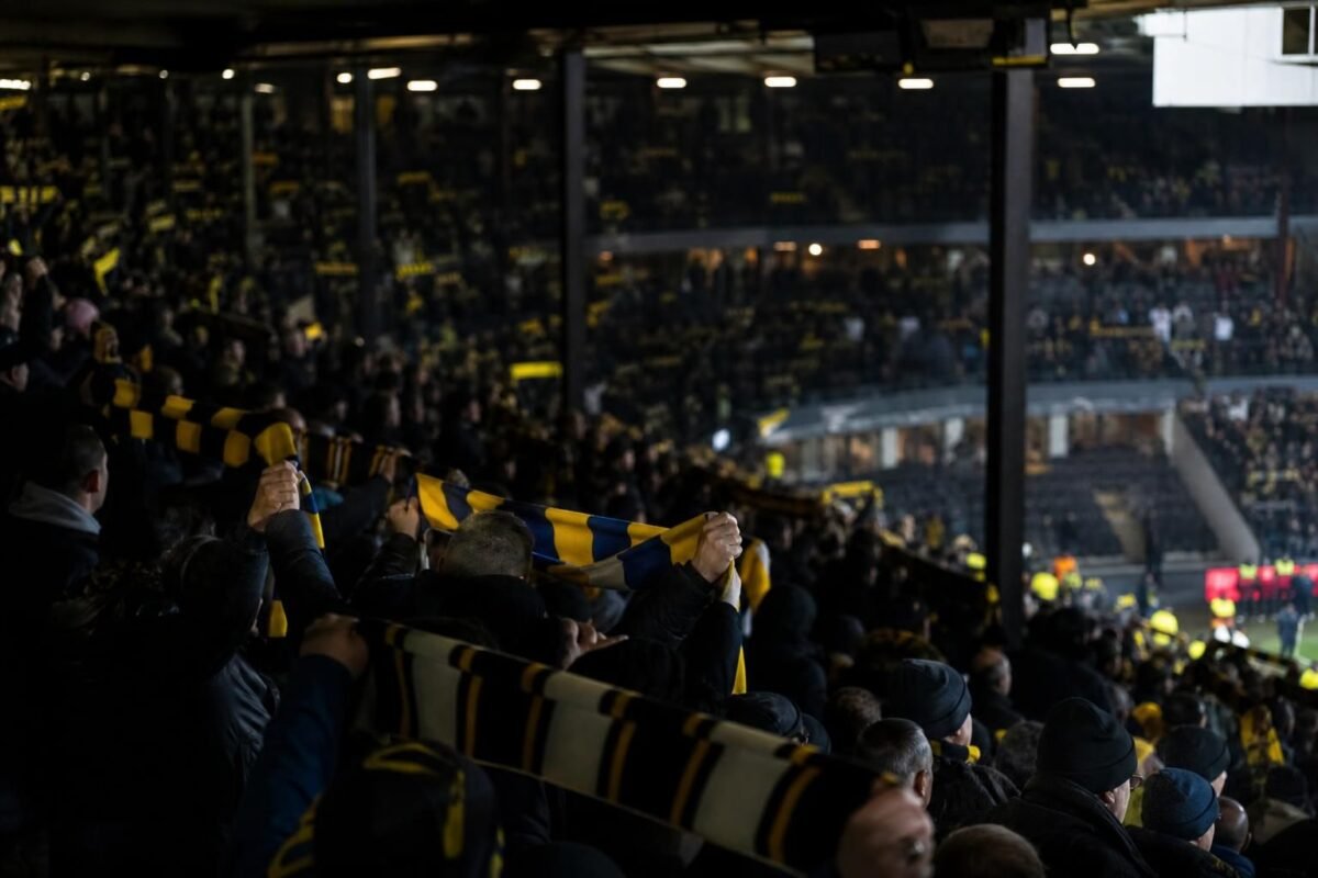 Supporters in een Belgisch stadion tijdens een gespannen debat over de zichtbaarheid van het voetbal