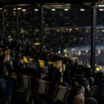 Supporters in een Belgisch stadion tijdens een gespannen debat over de zichtbaarheid van het voetbal