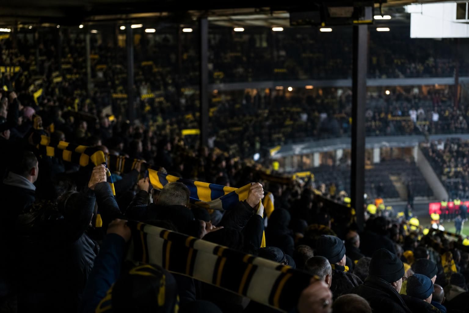 Supporters in een Belgisch stadion tijdens een gespannen debat over de zichtbaarheid van het voetbal