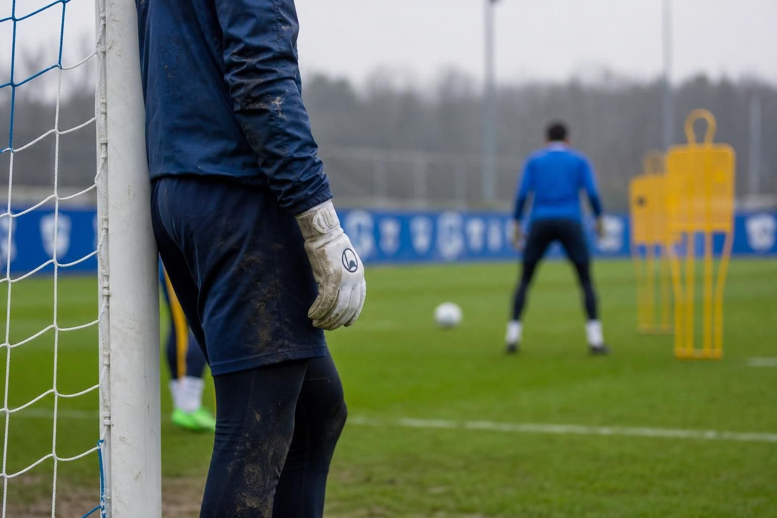 Keeperscontext bij KRC Genk met doelnet en handschoenen tijdens een gespannen trainingsmoment