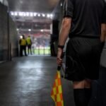 Tense stadium corridor scene with referee atmosphere and no identifiable people