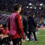 Jonge voetballer aan de zijlijn tijdens een invalbeurt in een stadion, zonder herkenbaar gezicht