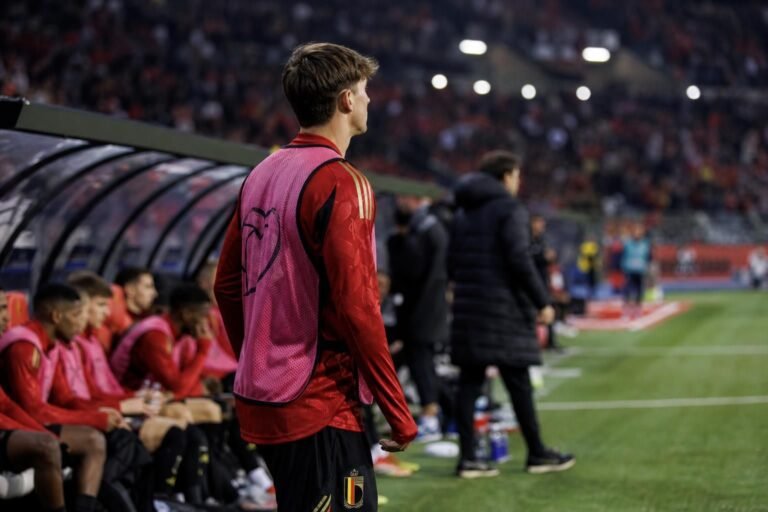 Jonge voetballer aan de zijlijn tijdens een invalbeurt in een stadion, zonder herkenbaar gezicht