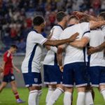 Engelse spelers vieren vanop afstand een doelpunt in een regenachtige oefeninterland tegen Costa Rica