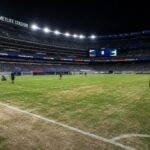 Een gespannen stadionbeeld met een droge grasmat voor een WK-wedstrijd