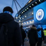 Transferachtige sfeer rond Manchester City met stadionlichten en spanning op de achtergrond