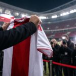 Transferpresentatie bij Ajax in rood-witte sfeer zonder herkenbare gezichten