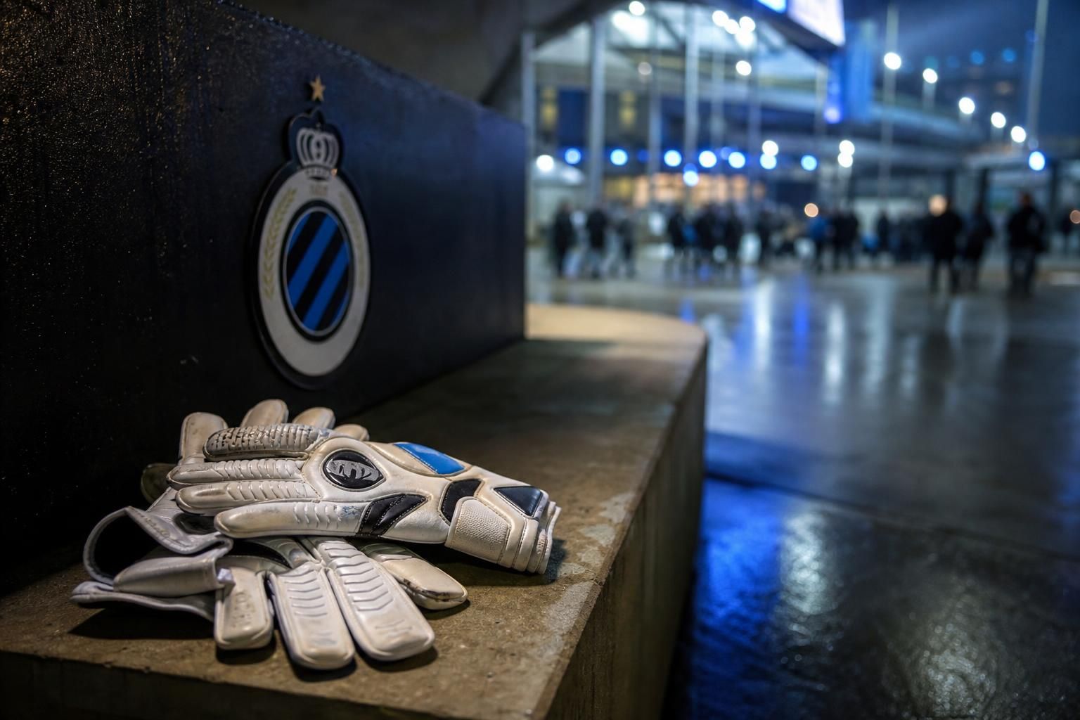 Keepershandschoenen in een stadionomgeving van Club Brugge als symbool voor de zoektocht naar een nieuwe doelman.