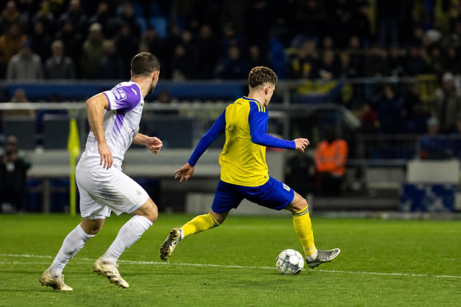 Een Cambuur-verdediger in een intens defensief duel onder stadionlichten.
