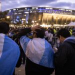 Supporters buiten een stadion tijdens de WK-finale kijken bezorgd naar ticketprijzen op een smartphone