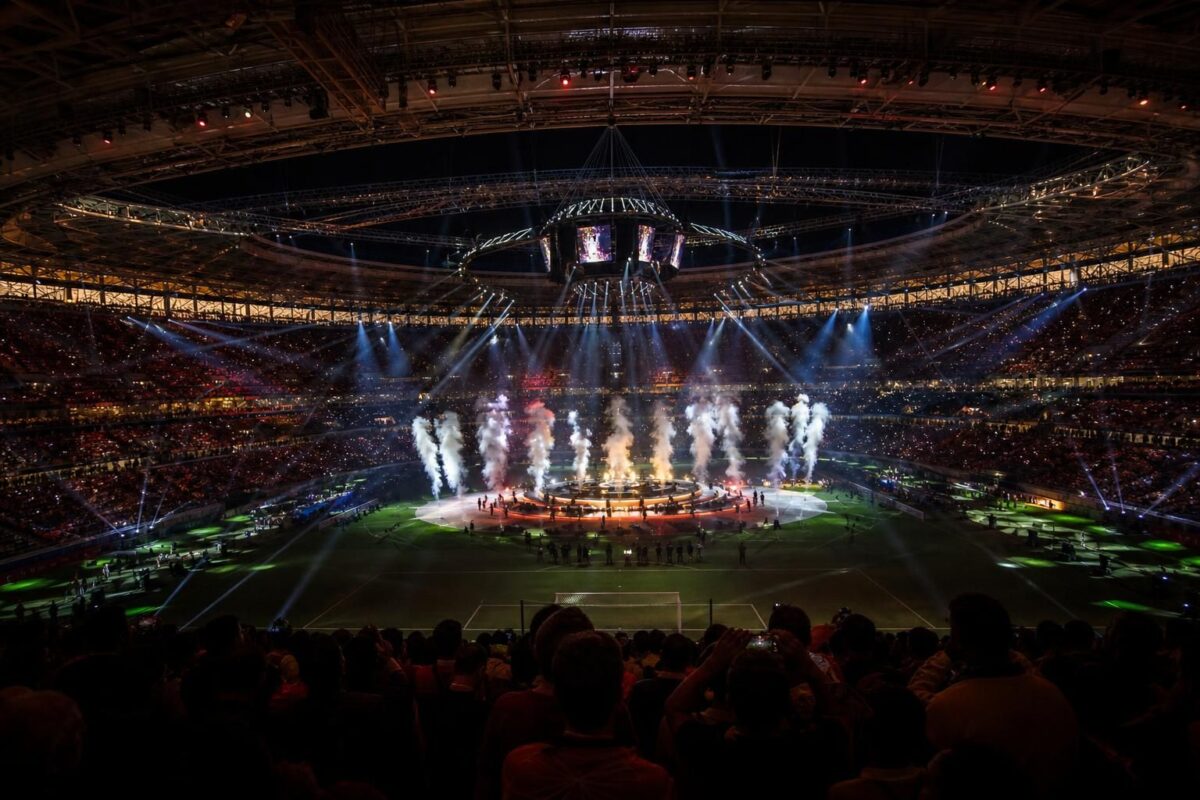Een fel verlicht stadion tijdens een WK-rustshow met volle tribunes en showlichten