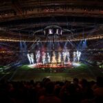 Een fel verlicht stadion tijdens een WK-rustshow met volle tribunes en showlichten