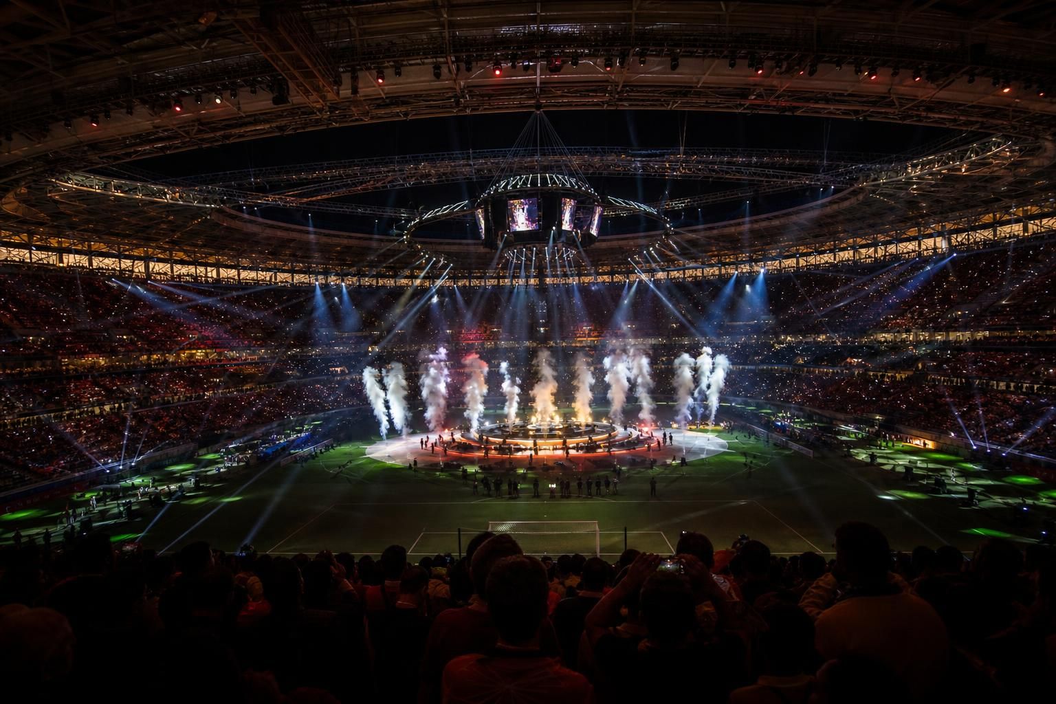 Een fel verlicht stadion tijdens een WK-rustshow met volle tribunes en showlichten