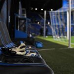 Goalkeepershandschoenen naast een bank in een blauw-zwarte stadionomgeving bij Club Brugge