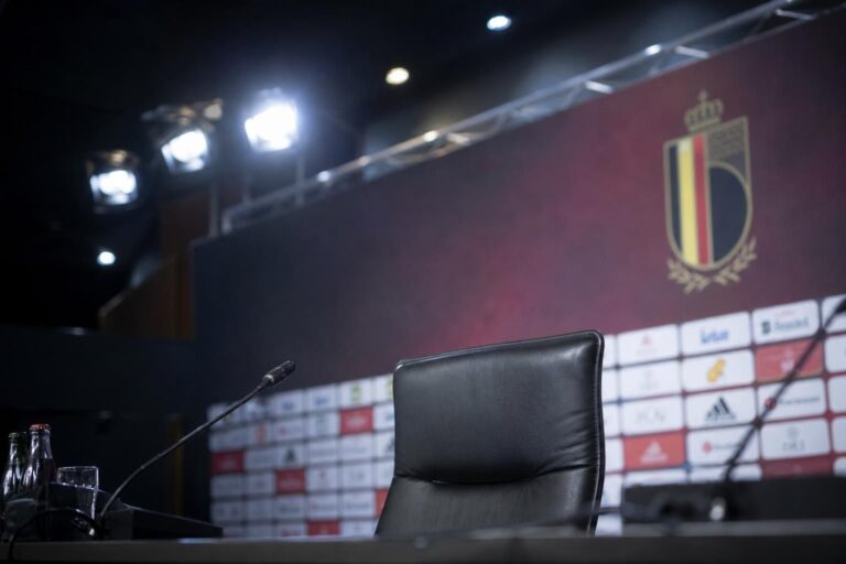 Lege persstoel met microfoons in een voetbalperszaal rond de Rode Duivels.