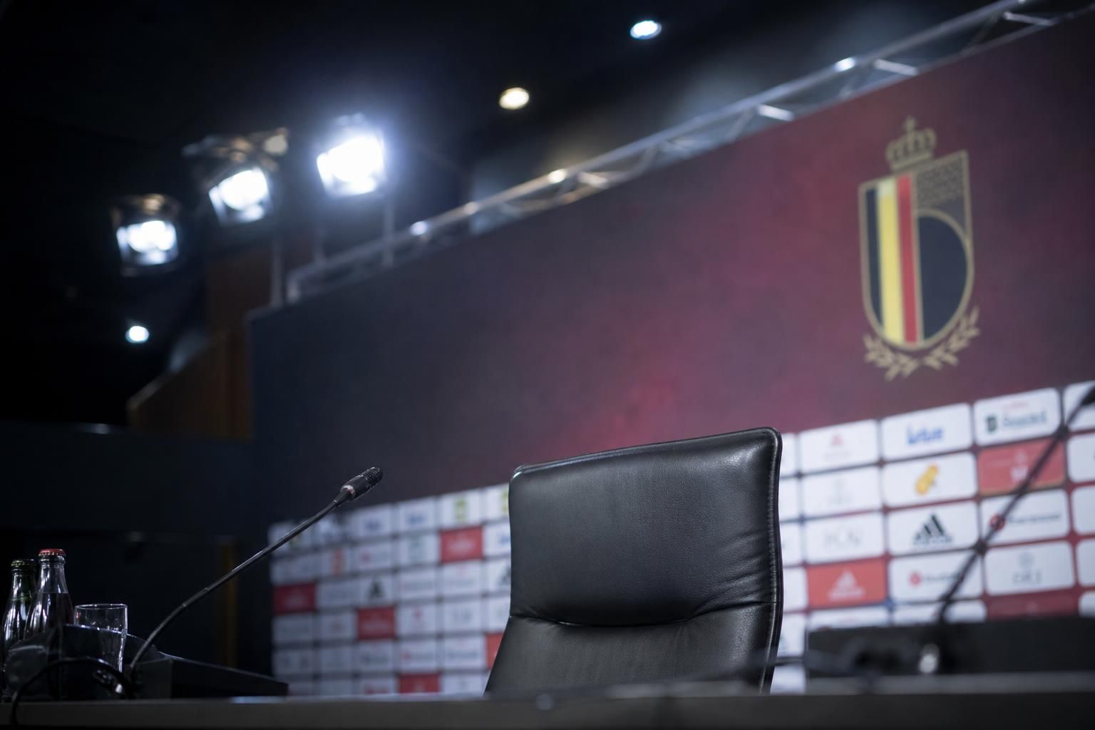 Lege persstoel met microfoons in een voetbalperszaal rond de Rode Duivels.