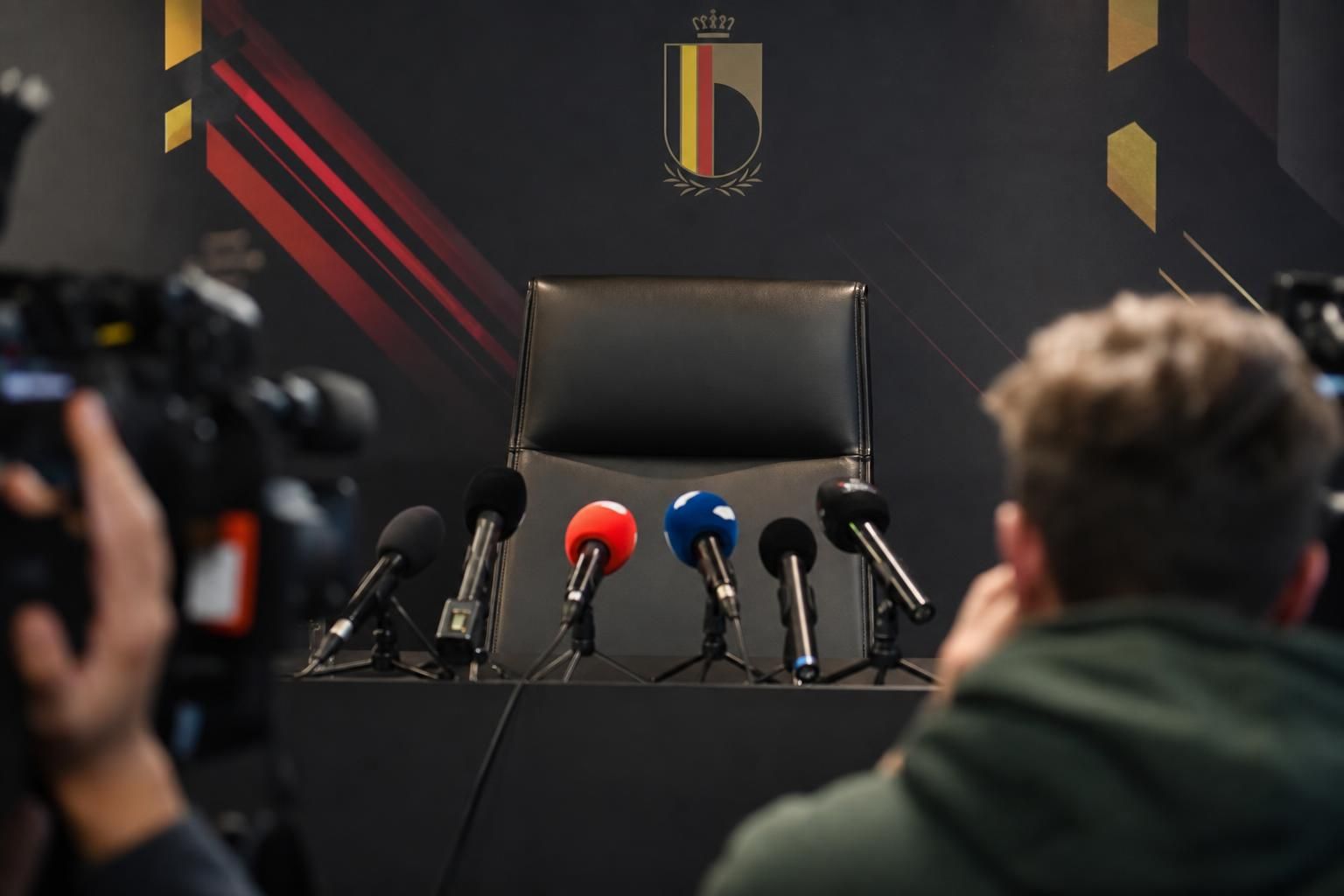 Lege persruimte van de Rode Duivels met microfoons en gespannen sfeer rond de zoektocht naar een bondscoach