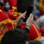 Spaanse voetbalsfeer met supporters en smartphone als symbool voor online reacties rond Inés García en Lamine Yamal