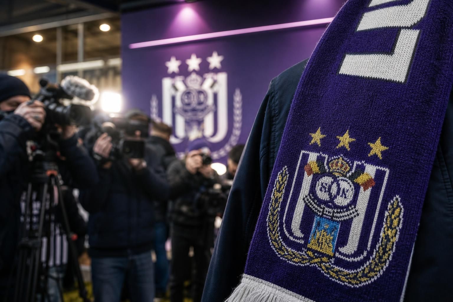 Transfercontext rond RSC Anderlecht met paarse clubkleuren en perscamera's zonder herkenbare gezichten