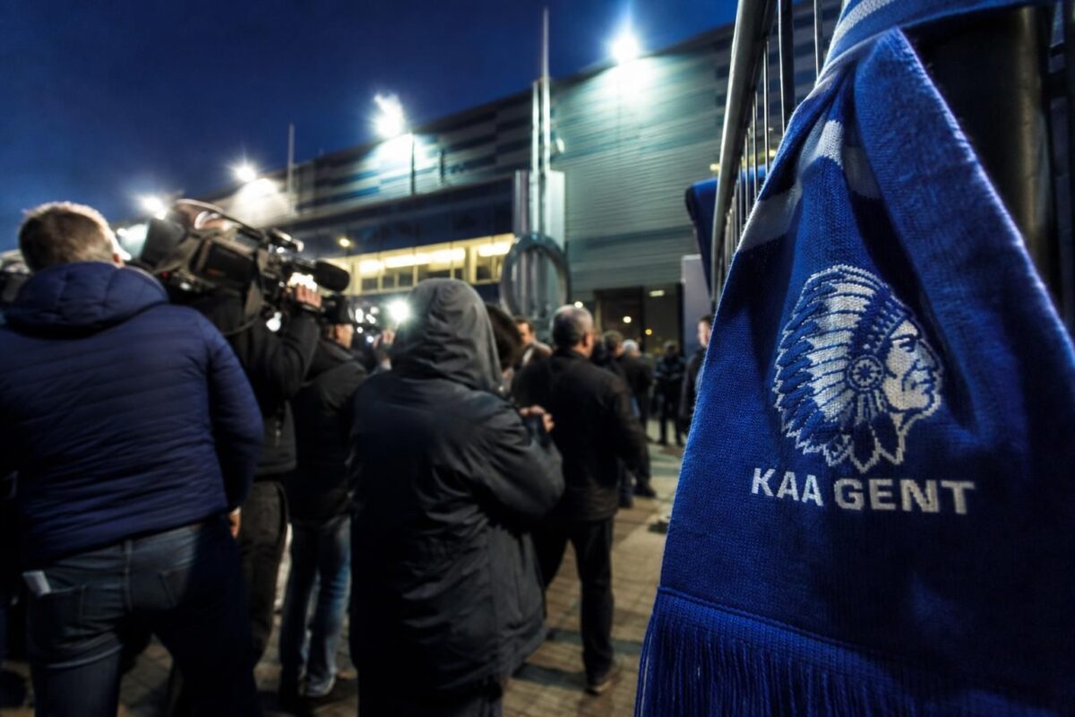 Transfercontext rond KAA Gent met stadionlicht en perssfeer zonder herkenbare gezichten