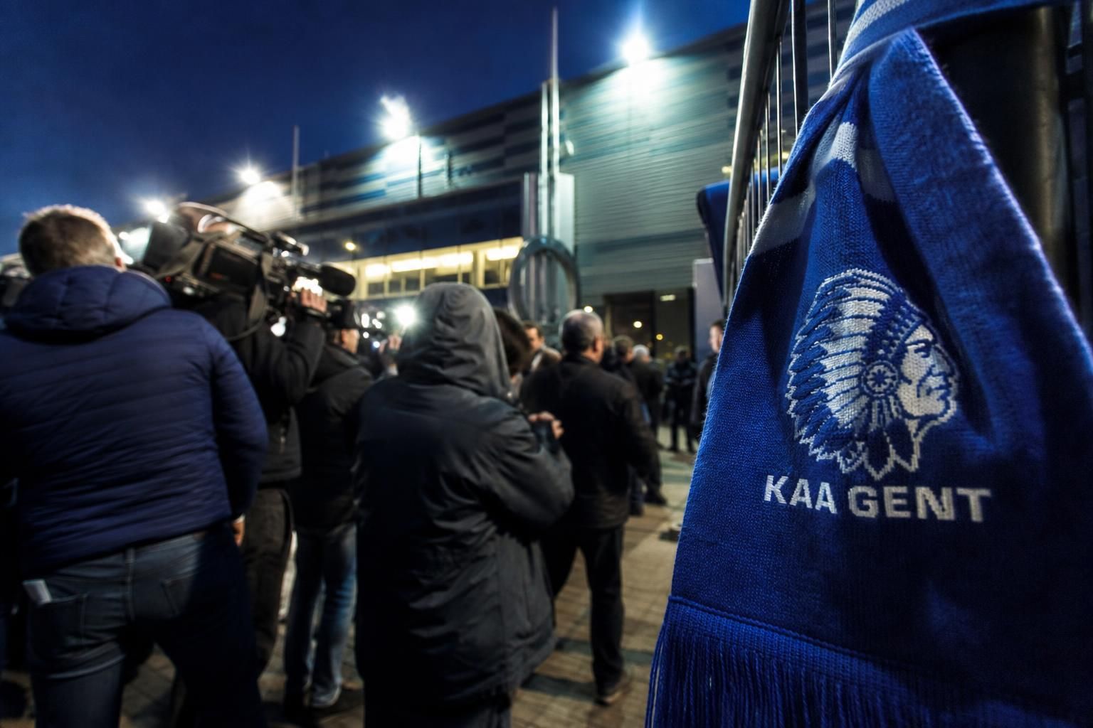 Transfercontext rond KAA Gent met stadionlicht en perssfeer zonder herkenbare gezichten