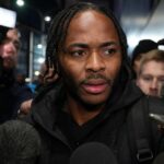 Raheem Sterling in een gespannen perscontext rond een voetbalstadion