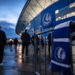 Transfercontext rond KAA Gent met stadionomgeving en blauw-witte clubkleuren zonder herkenbare gezichten
