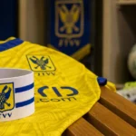 Aanvoerdersband op een geel-blauw STVV-shirt in de kleedkamer van Stayen