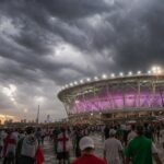 Dreigende WK-stadionsfeer voor Engeland-Mexico met supporters en donkere wolken.
