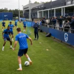 Spelers en staf van KRC Genk op het trainingsveld met pers langs de zijlijn