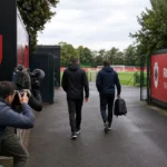 Anonieme stafleden en journalisten aan de ingang van de trainingsaccommodatie van Royal Antwerp FC