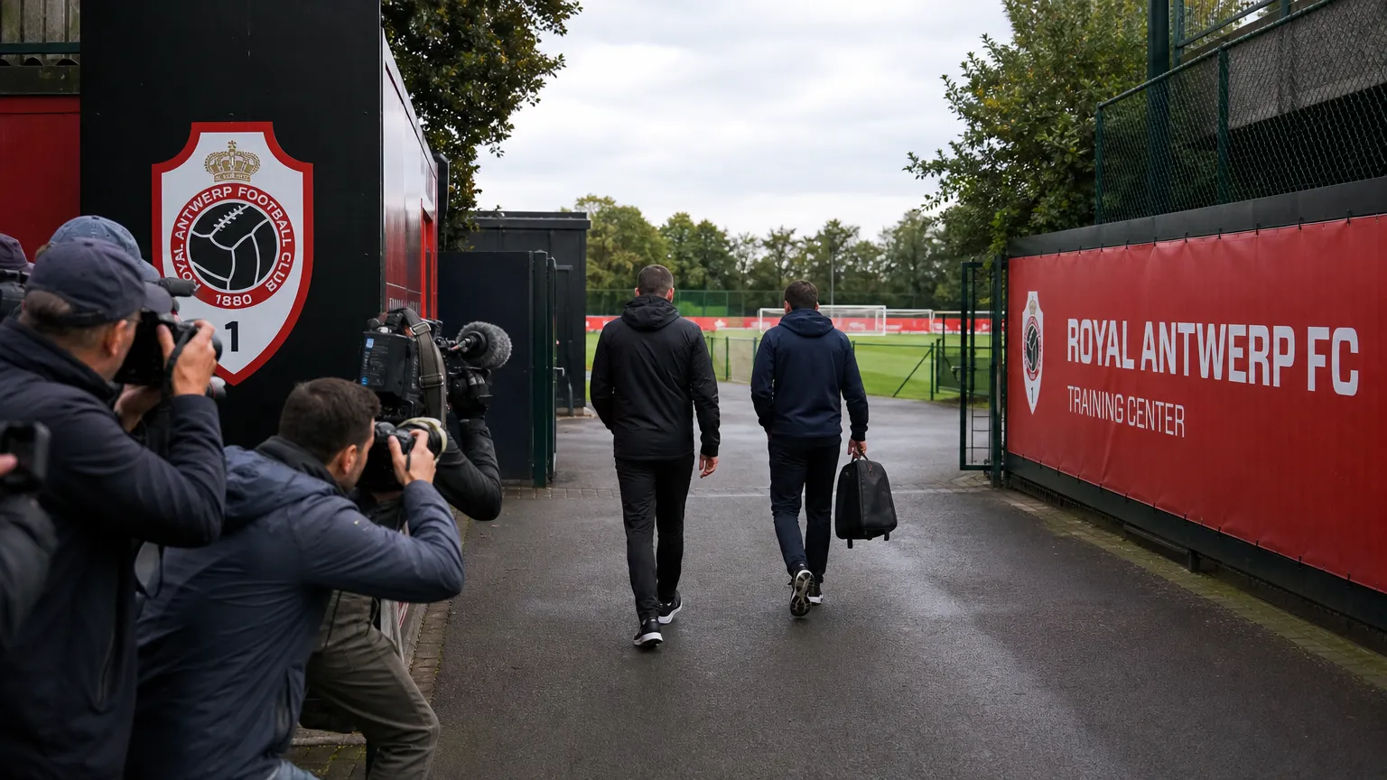 Anonieme stafleden en journalisten aan de ingang van de trainingsaccommodatie van Royal Antwerp FC