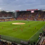 Spelers van KV Mechelen warmen in groep op in een gevuld stadion