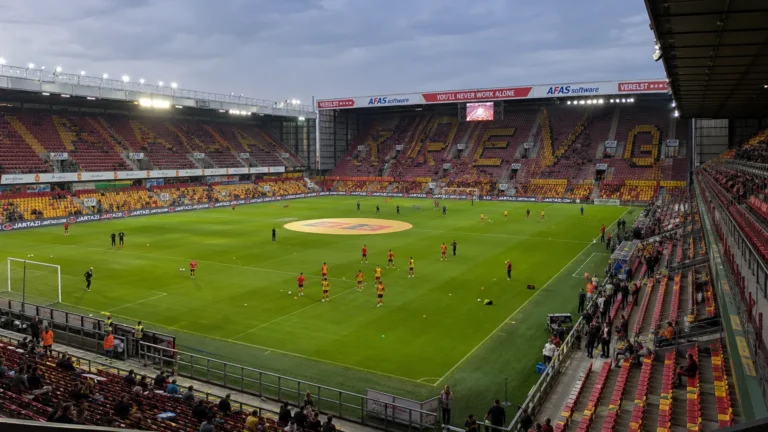 Spelers van KV Mechelen warmen in groep op in een gevuld stadion