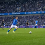 Brede wedstrijdscène met spelers van KRC Genk in het actuele thuistenue