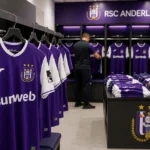 Materiaalmedewerkers rangschikken Anderlecht-tenues in een kleedkamer
