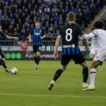 Brede wedstrijdscène met Club Brugge-spelers op het veld.