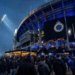 Supporters van Club Brugge in een stadionomgeving als symbool voor de financiële impact van een nieuw stadion.