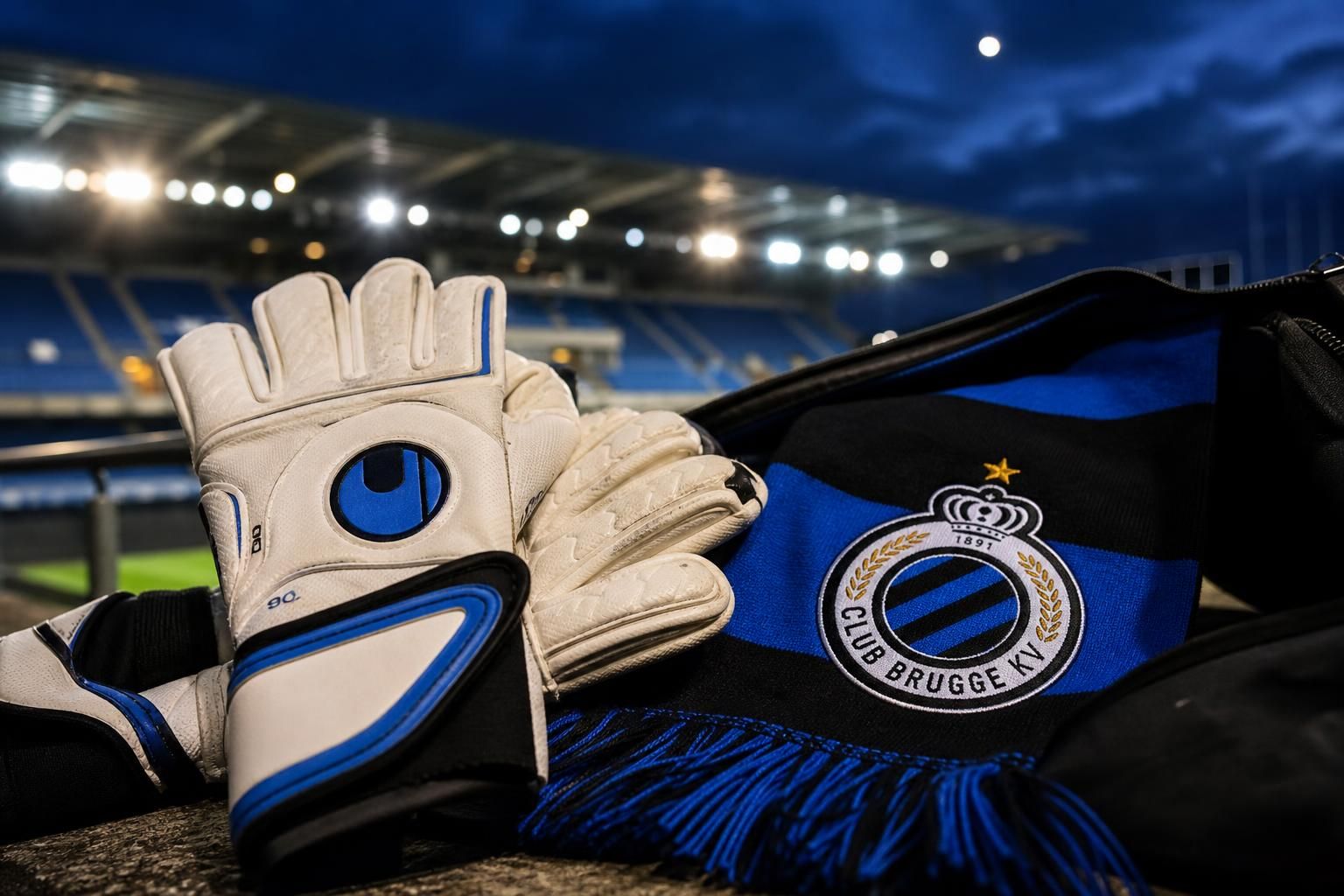 Transfercontext rond Club Brugge met keepershandschoenen en blauw-zwarte clubkleuren bij Jan Breydel.
