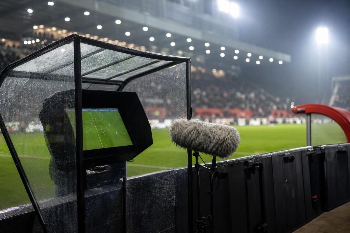 Scheidsrechter bij een VAR-moment in een gespannen stadionomgeving