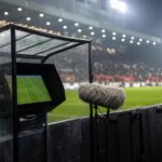 Scheidsrechter bij een VAR-moment in een gespannen stadionomgeving