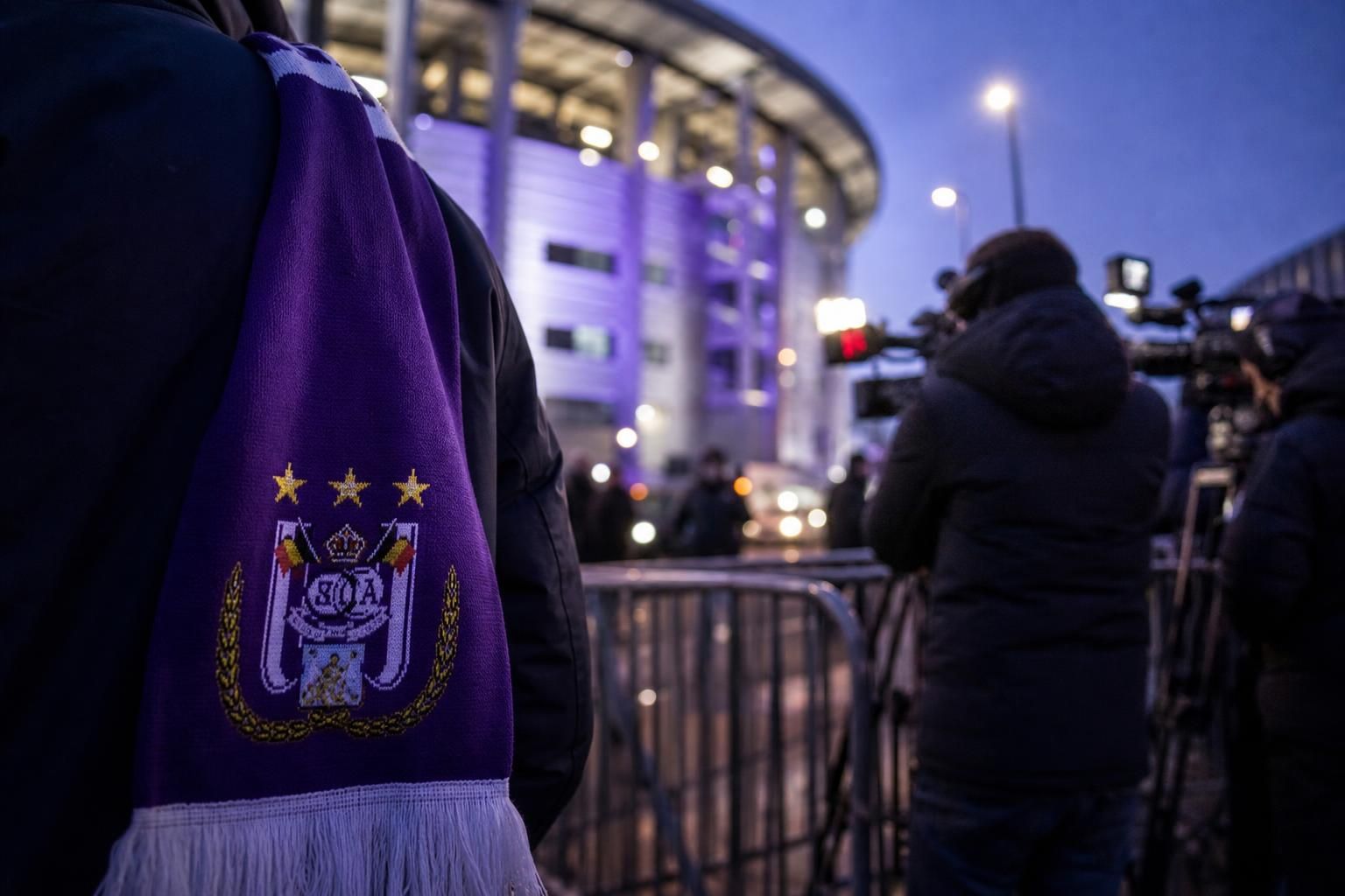 Transfercontext bij RSC Anderlecht met paarse sjaal en perscamera's zonder herkenbare gezichten